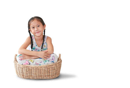 Portrait of smiling asian little kid girl sitting in rattan picnic basket isolated on white background with copy spaceの写真素材