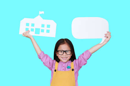 Smiling asian little child girl holding mock-up paper school and empty blank speech bubble isolated...