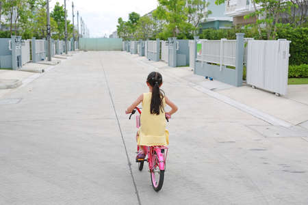 Asian little child girl riding bike on street. Bear viewの写真素材