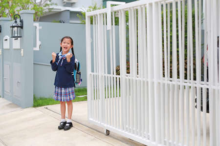 Confident asian little kid girl in kindergarten school uniform raise hands up expression before...