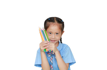Asian little girl in school uniform holding color pencils over white background. Education and...