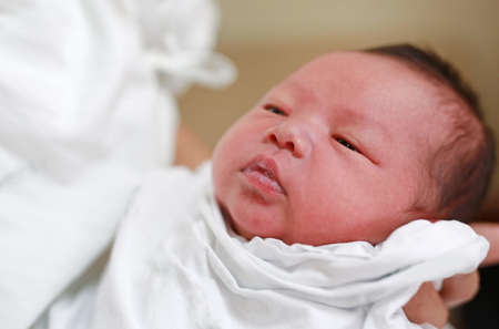 Infant baby feeding milk from glass cup.