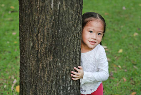 Portrait of cute little child girl and nature. Kid hugging a tree.の写真素材