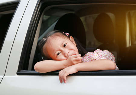 little asian child looking camera from the window of the car.の写真素材