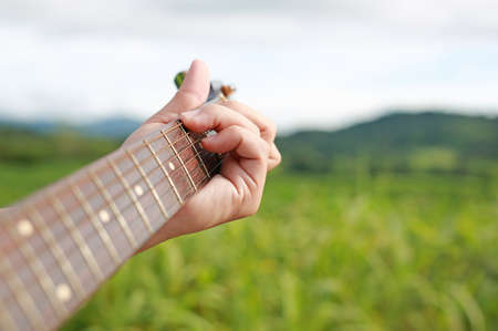 Hand playing on acoustic guitar in the nature.の写真素材