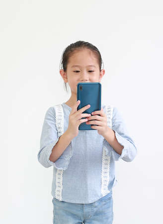 Portrait smiling asian little child girl using smartphone isolated on white background.の写真素材