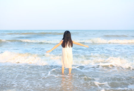 Back view of asian little child girl relaxing on the beach.の写真素材
