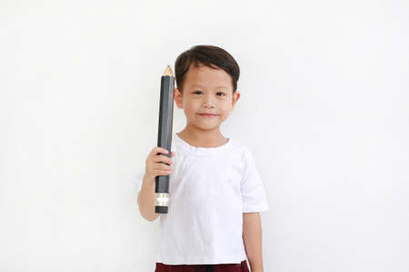 Adorable Asian little boy holding big pencil and looking camera over white background. Kid and...
