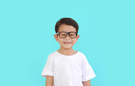 Portrait of smiling asian little boy child wearing glasses isolated over cyan background