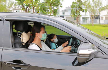 Asian mother and daughter wear hygiene face mask sit in car during outbreak