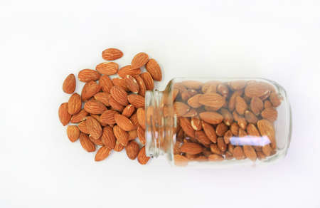 Almonds nuts pour from glass bottle isolated on white background. Top viewの写真素材
