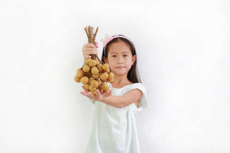 Pretty Asian girl kid holding bunch of longan fruit giving for you over white background. Focus at fruit in his handsの写真素材