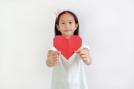 Young girl kid show red heart sign against white background. Focus at red heart paperの写真素材