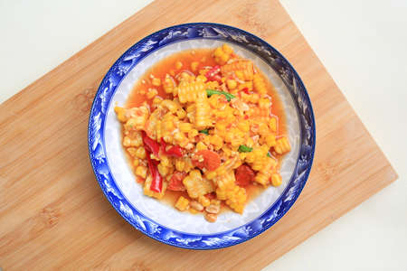 Thai style chili and lime corn salad in plate against wooden board. Spicy vegetable salads. Top view