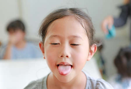 Funny face Asian little girl child showing stick tongue outの写真素材
