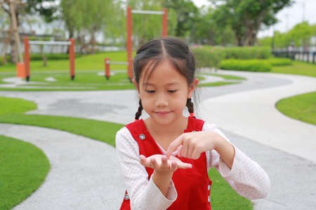 Asian little girl kid gesture finger touch something and looking without theme on hands while in the garden.の写真素材