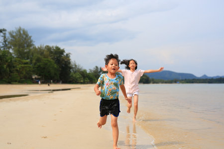 Asian little boy child and girl kid having fun running on tropical sand beach at sunrise. Happy family sister and brother enjoy in summer holiday.の写真素材