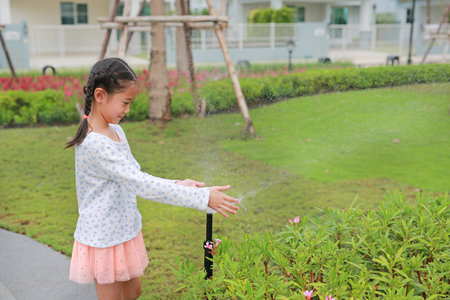 Little Asian girl having fun to play water of watering the plants.の写真素材