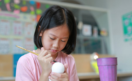 Asian girl painting a doll with watercolor. Kid with water color painting activity.の写真素材