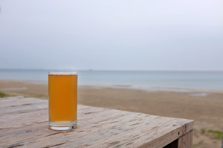 Glass of beer on the wood table background near the beach.の写真素材