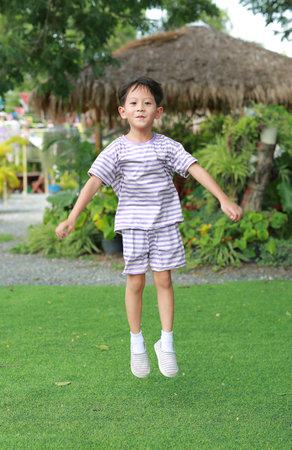 Happy Asian boy child jumping in the garden outdoor.の写真素材