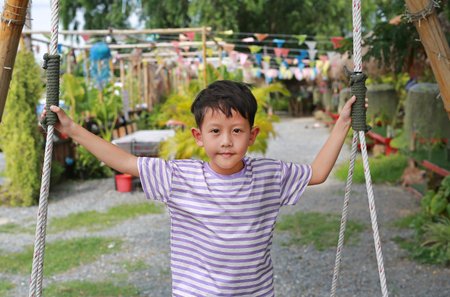 Portrait of Asian little boy play on the swing in the garden outdoor.の写真素材