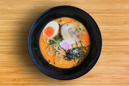 Tsukemen Ramen Asian noodles with chashu Pork, seaweed and boiled egg in black bowl on bamboo wooden background, top view.の写真素材