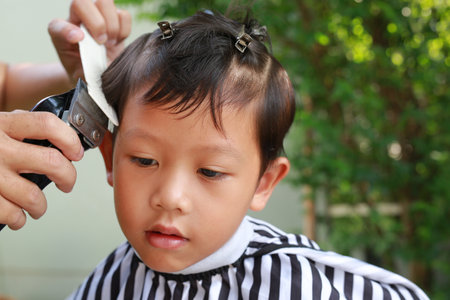 Asian boy cut in hairdresser's machine in the gardenの写真素材