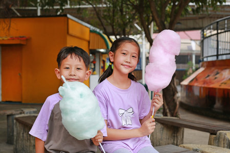 Happy Asian children boy and girl having fun eating cotton candy in the public park.の写真素材