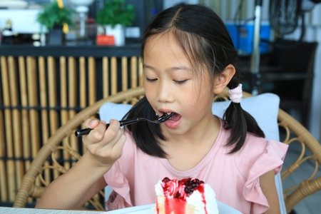 Portrait of Asian young girl child eating strawberry cake at the cafe.の写真素材