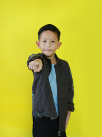 Portrait Asian little boy wear jacket pointing at you while standing and looking straight at camera...