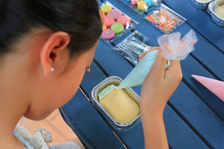 Portrait Asian girl child making and decorating cake DIY.