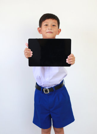 Soft focus Asian boy in primary or elementary school uniform showing tablet computer blank screen...
