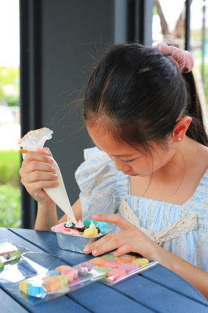 Portrait Asian girl child making and decorating cake DIY.の写真素材