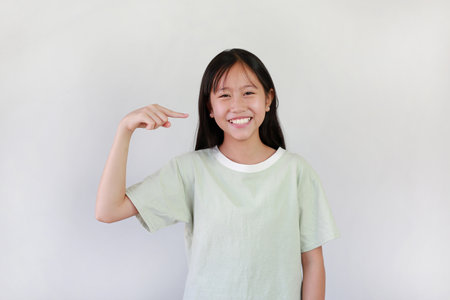 Asian pretty girl with big smile pointing forefinger at her face, teeth or blunt bangs hair on white studio background.の写真素材