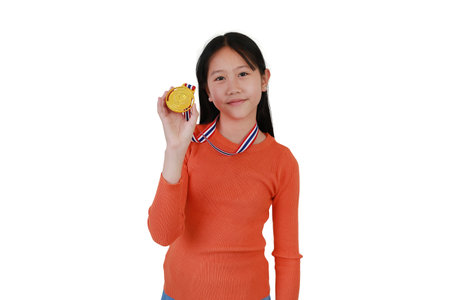 Portrait of happy Asian girl child showing gold medal on white studio background. Kid celebrating victory gesture concept.の写真素材