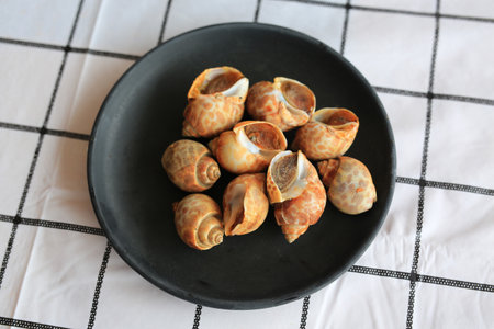 Grilled sweet clams in black plate on the table. Top view.