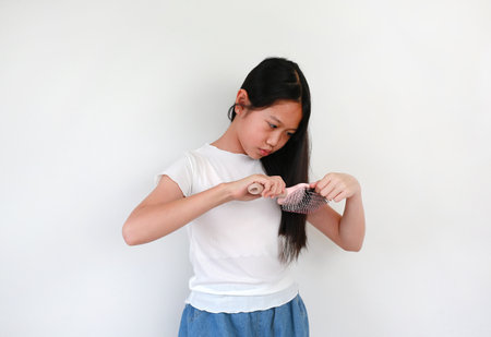 Portrait of Asian girl child combing long hair isolated on white background. Healthcare concept.
