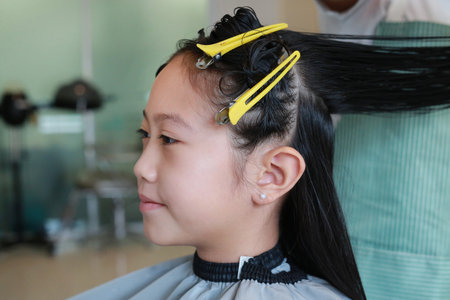Portrait of Asian girl child getting her haircut in a beauty salon. Close up.の写真素材