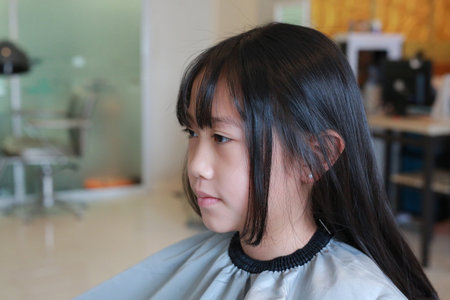 Portrait of Asian girl child getting her haircut in a beauty salon. Close up.の写真素材
