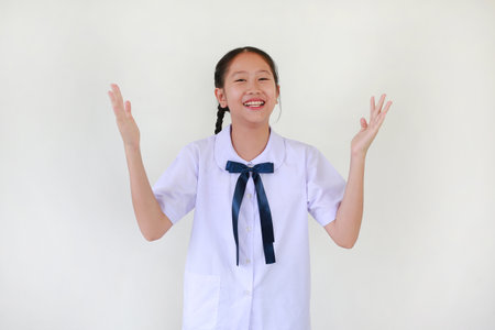Cheerful pretty Asian student girl in school uniform open hand wide while standing against white background.の写真素材