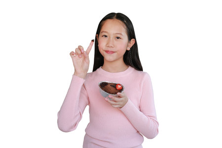 Portrait of pretty Asian girl child showing chocolate cake on index finger isolated on white background.の写真素材