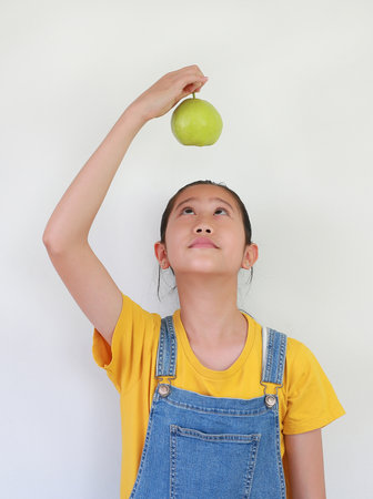Portrait of Asian girl kid holding a fresh guava above over head isolated on white studio background.の写真素材
