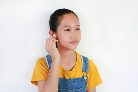 Asian girl kid using wireless headphones enjoy with music on white background.の写真素材