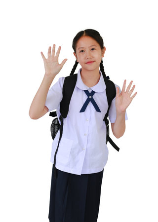 Portrait of Asian student girl in school uniform waving hand hello while carrying backpack bag...