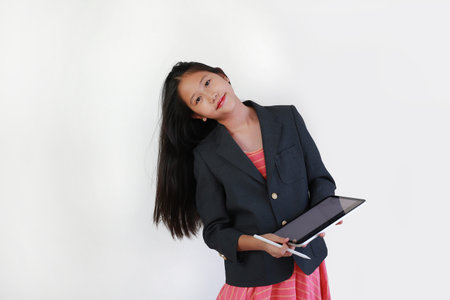 Portrait of young Asian girl in business-style blazer and dress holds digital tablet and stylus,...