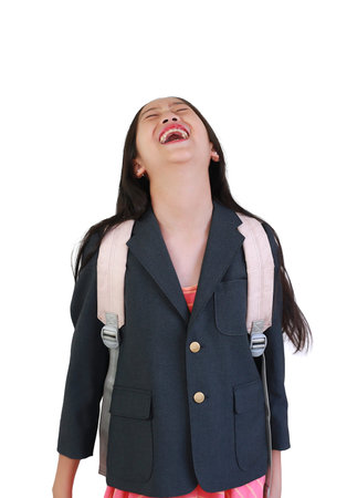 Cheerful schoolgirl in navy blazer and backpack laughing out loud with her head tilted back, expressing pure joy and excitement for her education journey.の写真素材