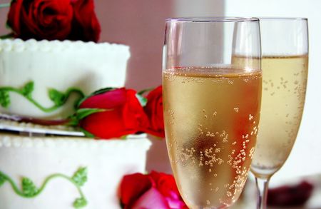 Champagne glasses and wedding cake with rosesの写真素材