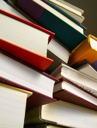 Various hardcover books stacked next to each otherの写真素材