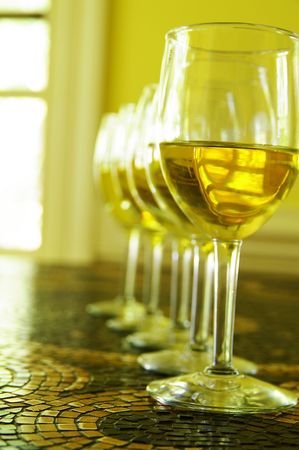 white wine glasses in a row, on tile tableの写真素材